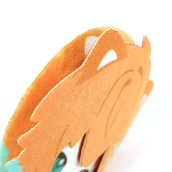 Close-up of custom plush head button pin with orange anime-style hair and blue eyes