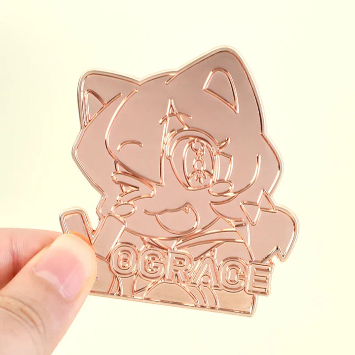 Hand holding custom rose gold die struck pin with anime cat face design and engraved text.