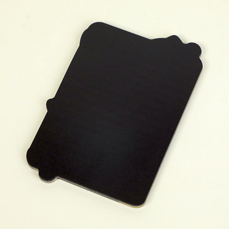 Black rectangular acrylic fridge magnet with decorative corners on a light background
