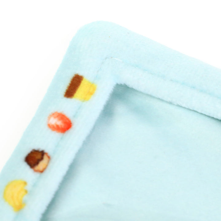 Close-up of light blue plush card holder corner with colorful food pattern trim